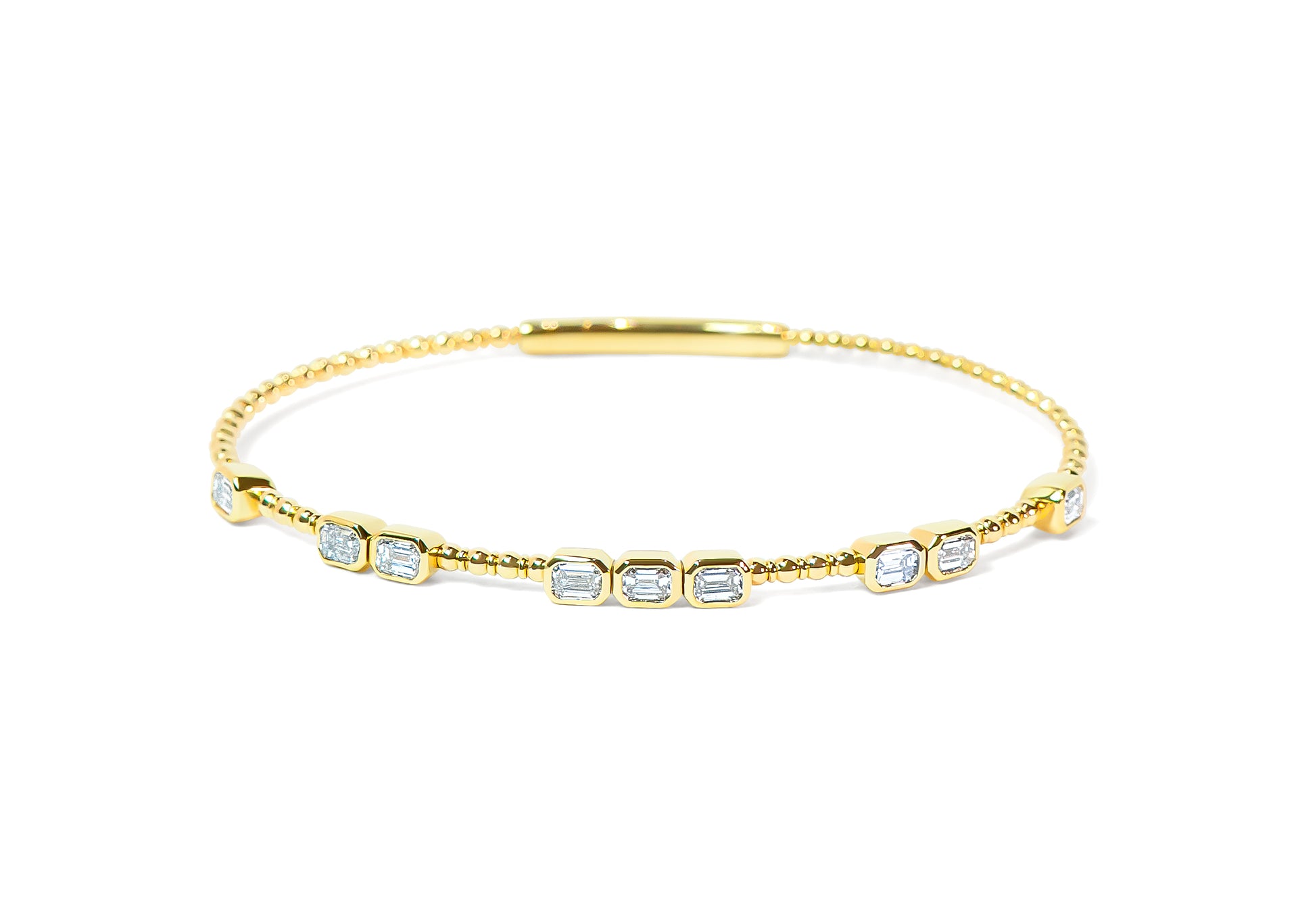 Gold flexible bangle with bezel emerald cut diamonds on a white background