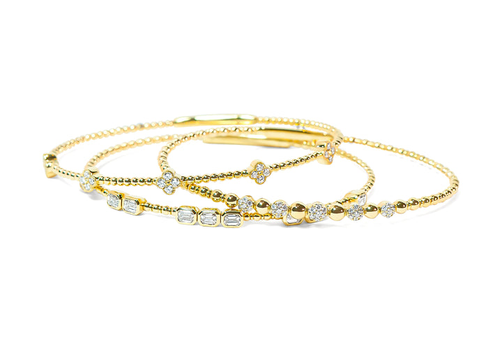 Set of gold bracelets with diamond accents on a white background