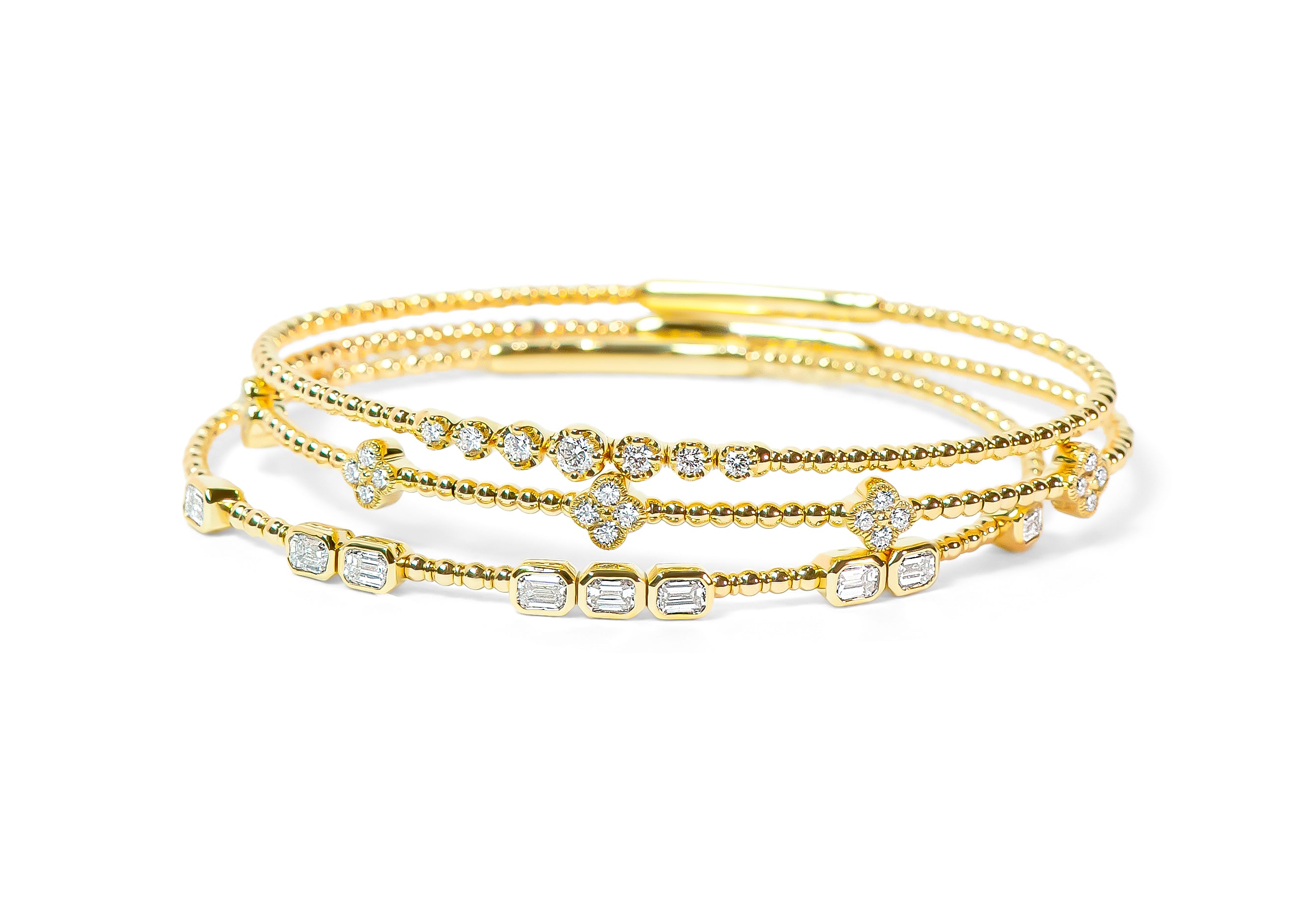 Set of gold bracelets with diamonds on a white background