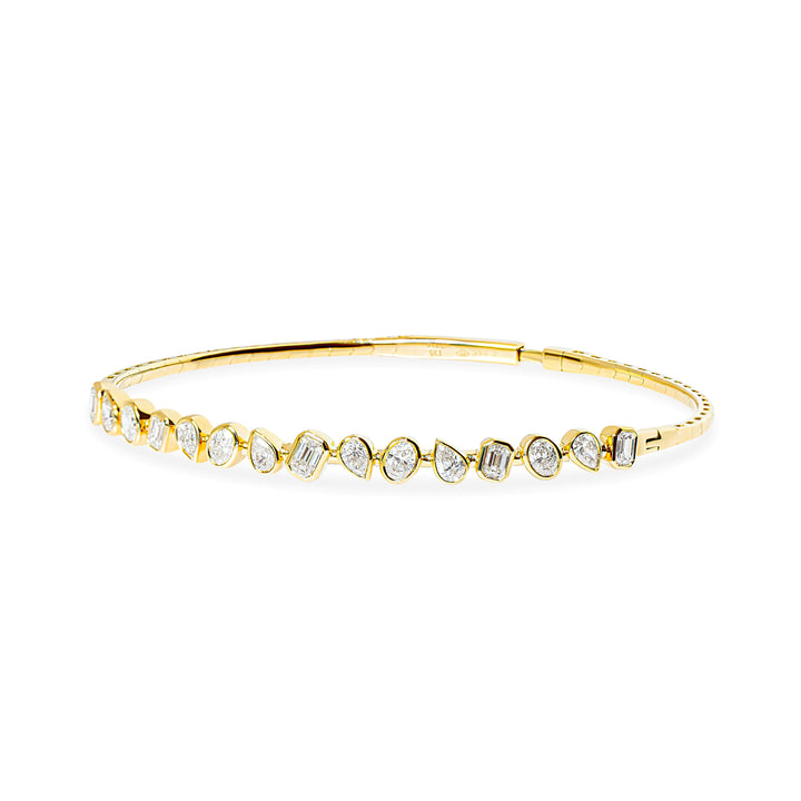 A delicate gold flexible bangle bracelet featuring a row of bezel-set emerald-cut, pear, and oval natural diamonds, photographed on a solid white background.