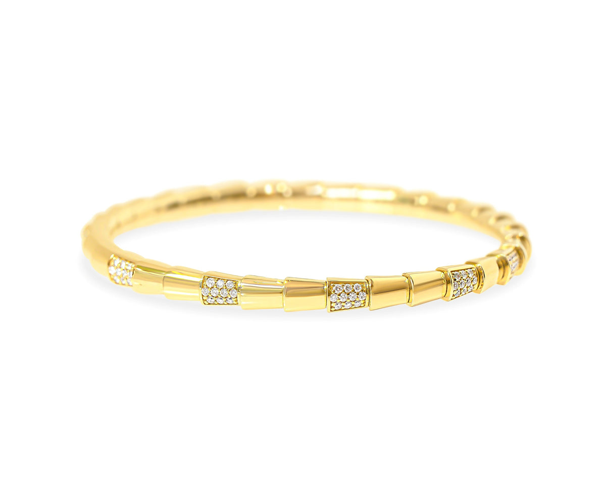 A gold stretchable serpent bangle bracelet with small diamond-set geometric accents, photographed on a clean white background.