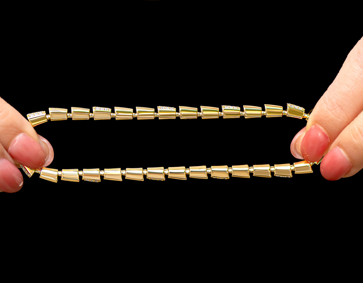 A pair of hands stretching a flexible stretch diamond gold bracelet against a solid black background.