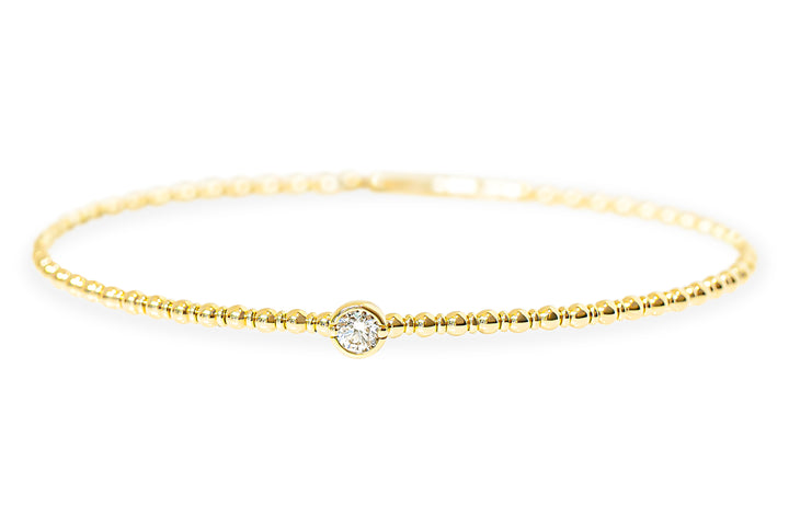 A delicate yellow gold beaded textured bangle with a single bezel-set round diamond at the center, displayed against a clean white background.