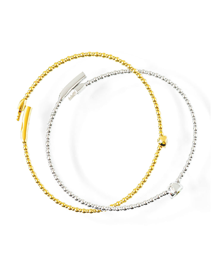 Two beaded flexible bangles, one gold and one silver, displayed on a clean white background.