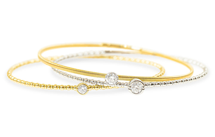 Three delicate bangle bracelets stacked together on a white background, featuring yellow gold, white gold, and silver-tone chains with round-cut diamond accents.