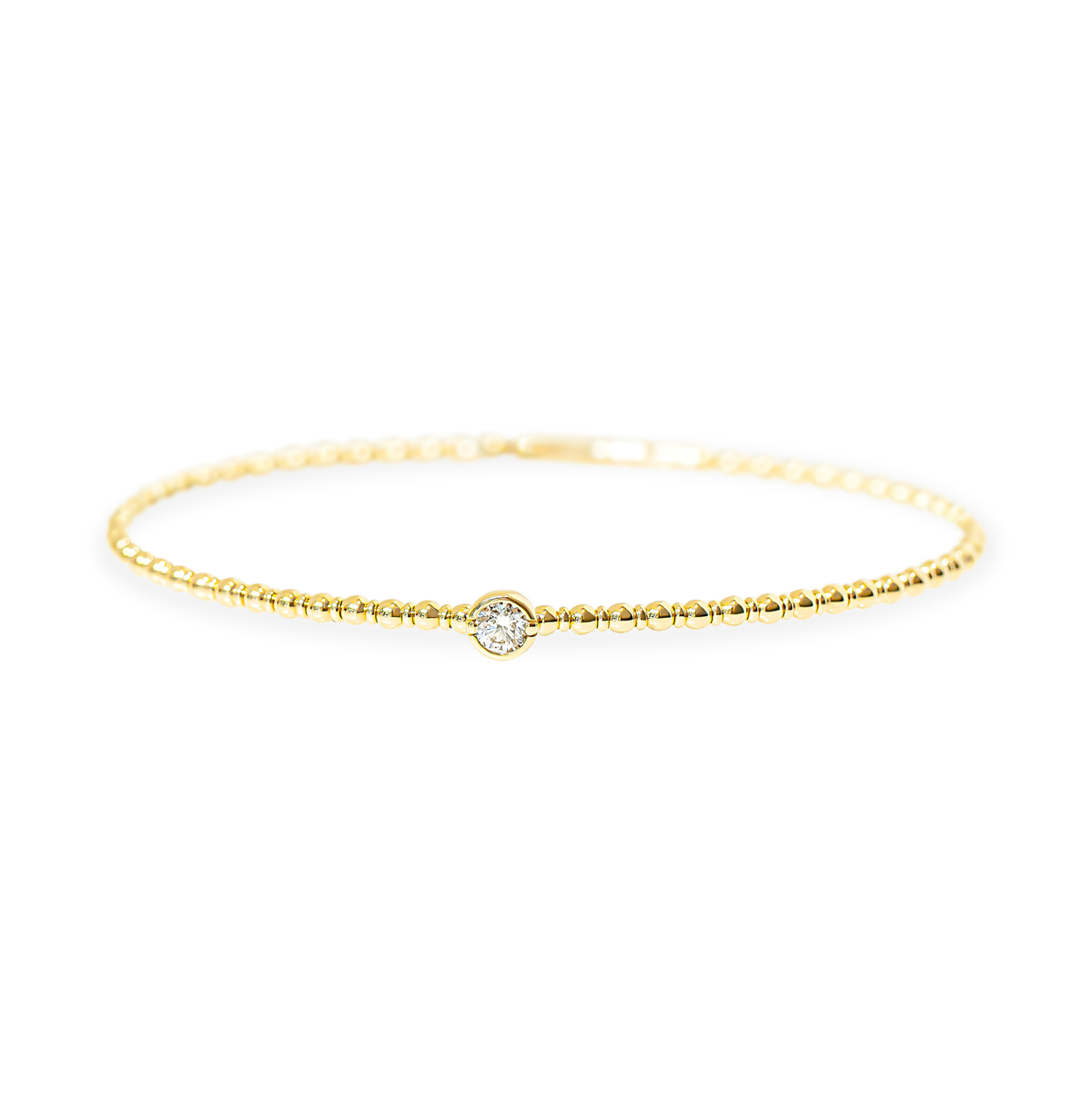 A delicate yellow gold beaded textured bangle with a single bezel-set round diamond at the center, displayed against a clean white background.