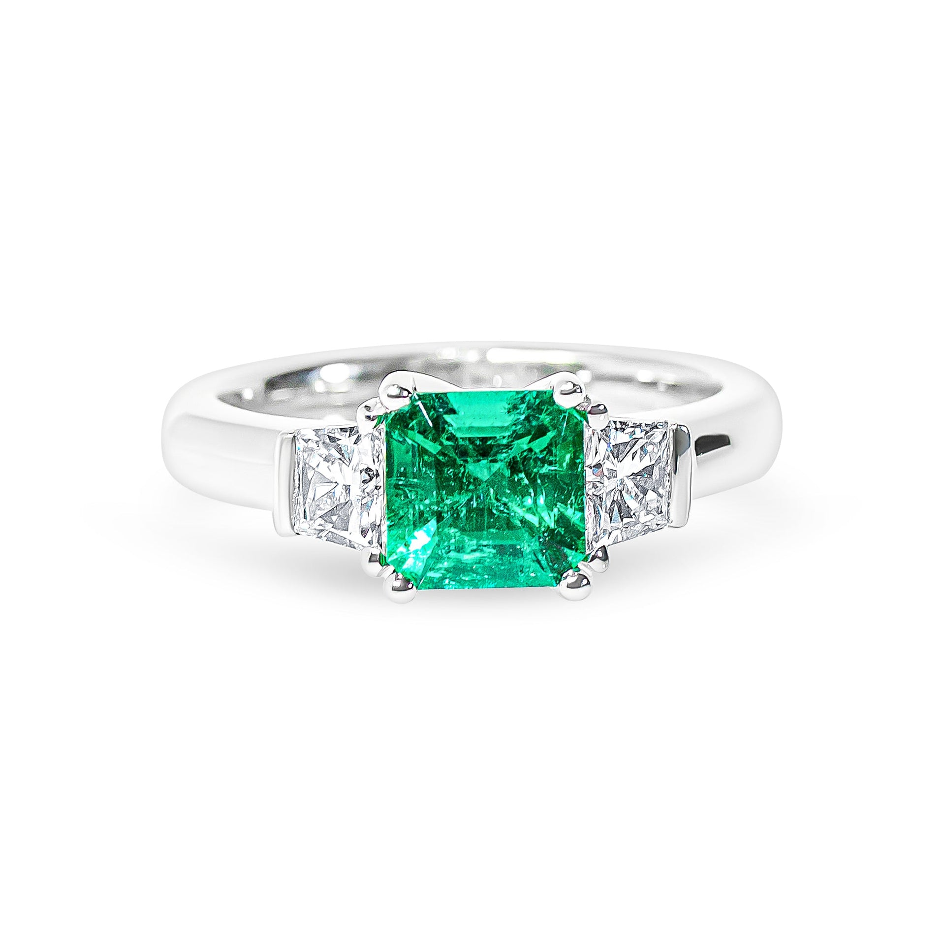 Platinum ring with a green emerald and diamonds on a white background