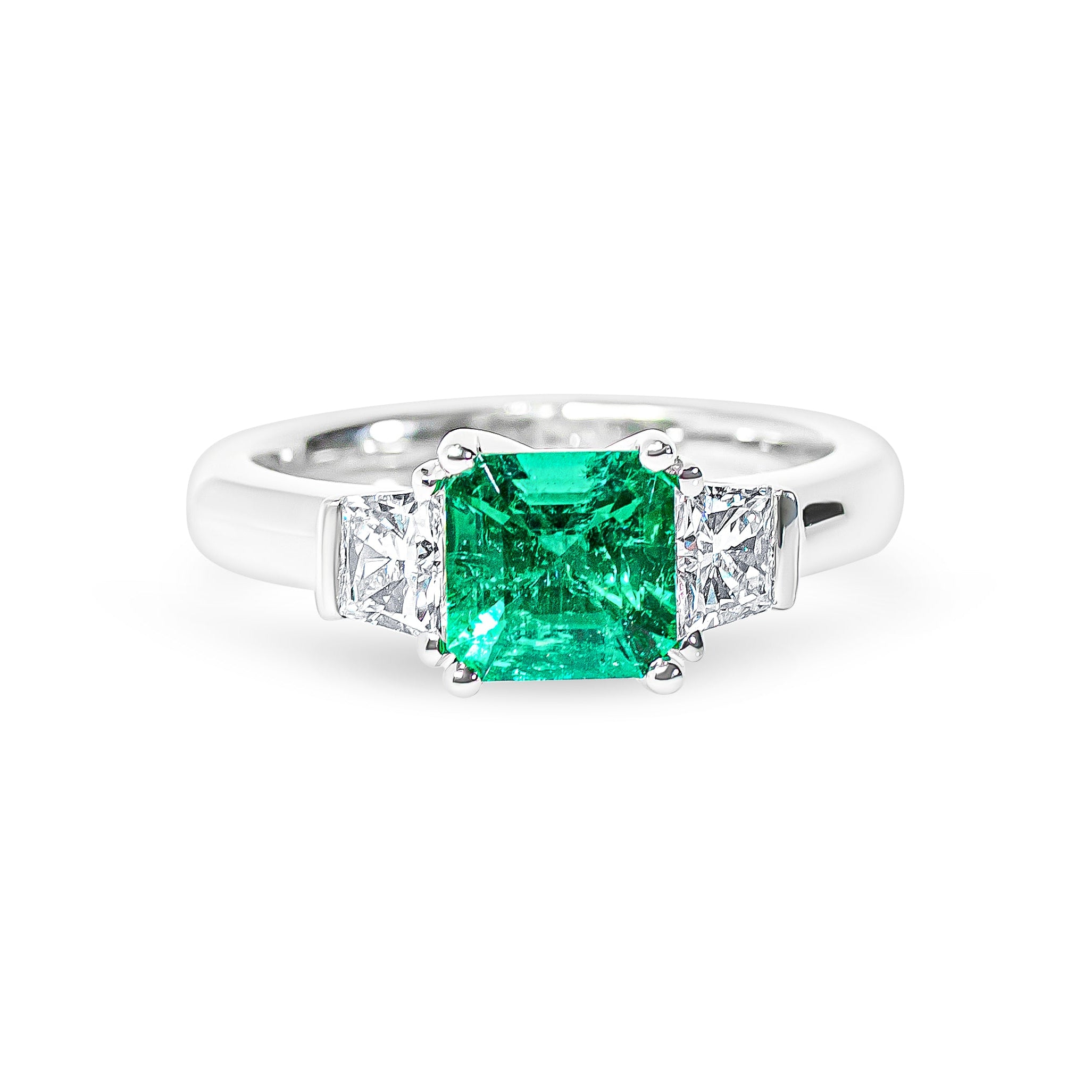 Platinum ring with a green emerald and diamonds on a white background