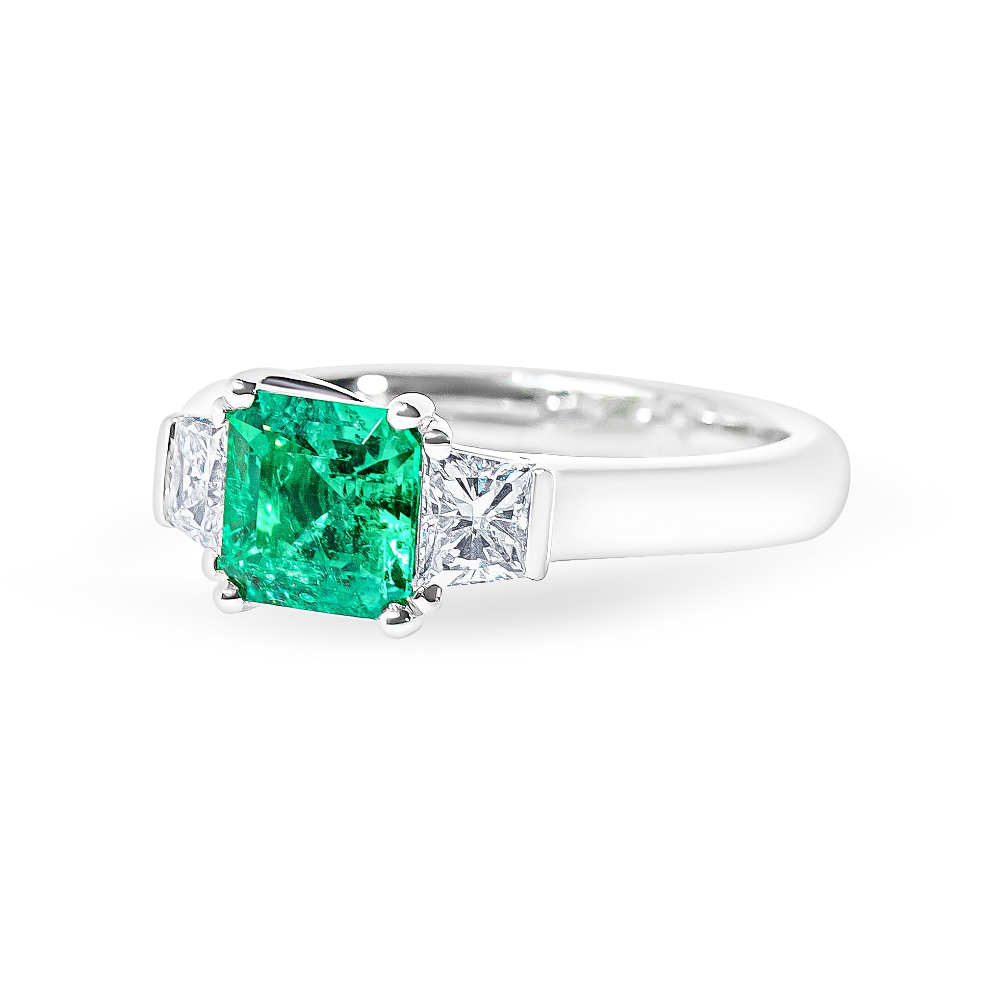 Platinum ring with a green emerald and diamonds on a white background