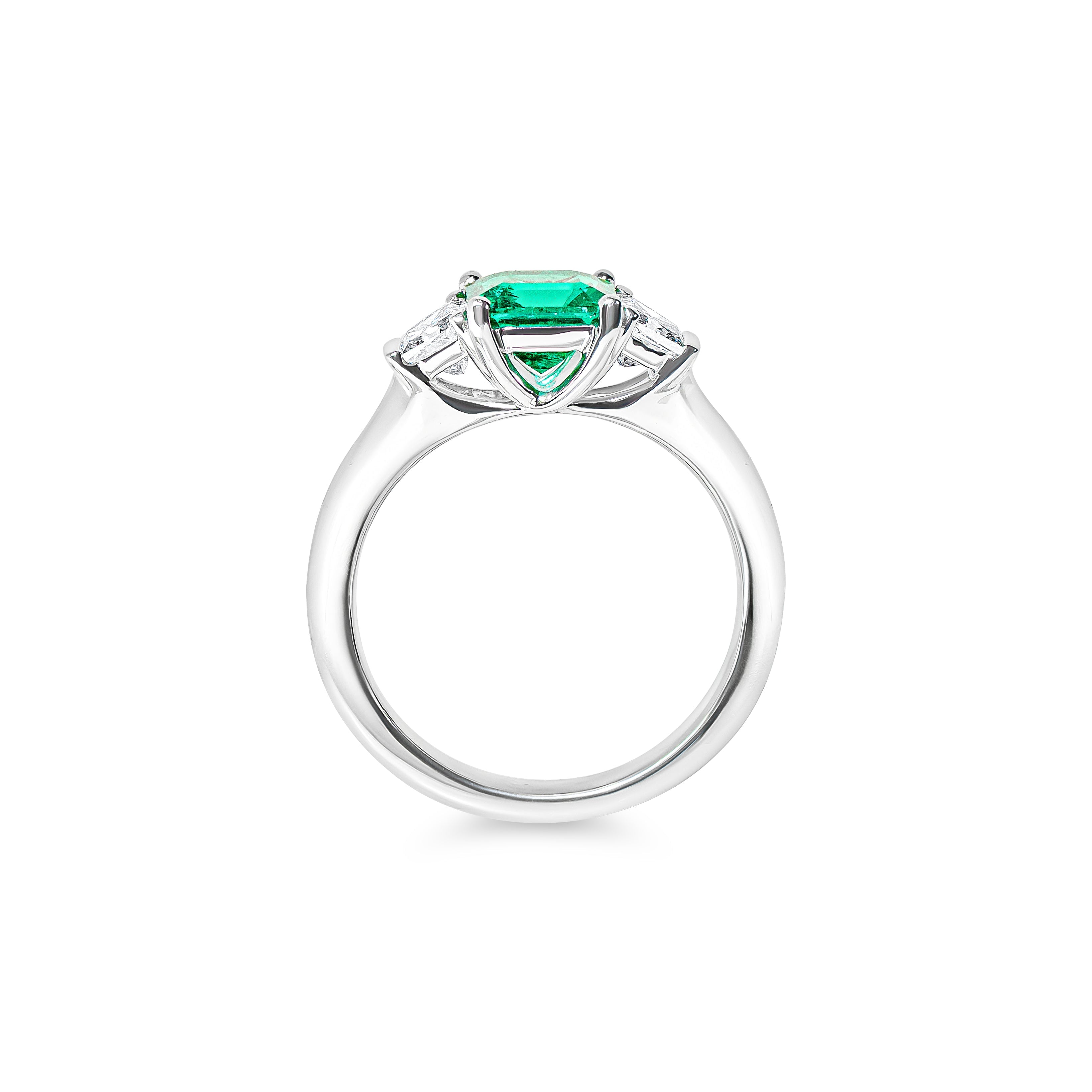 Platinum ring with a green emerald and diamonds on a white background