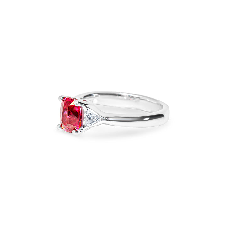 Platinum ring with a red ruby and two trillion diamonds on a white background