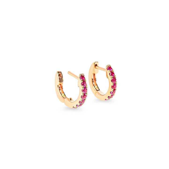Rose gold hoop earrings with red-pink rubies on a white background