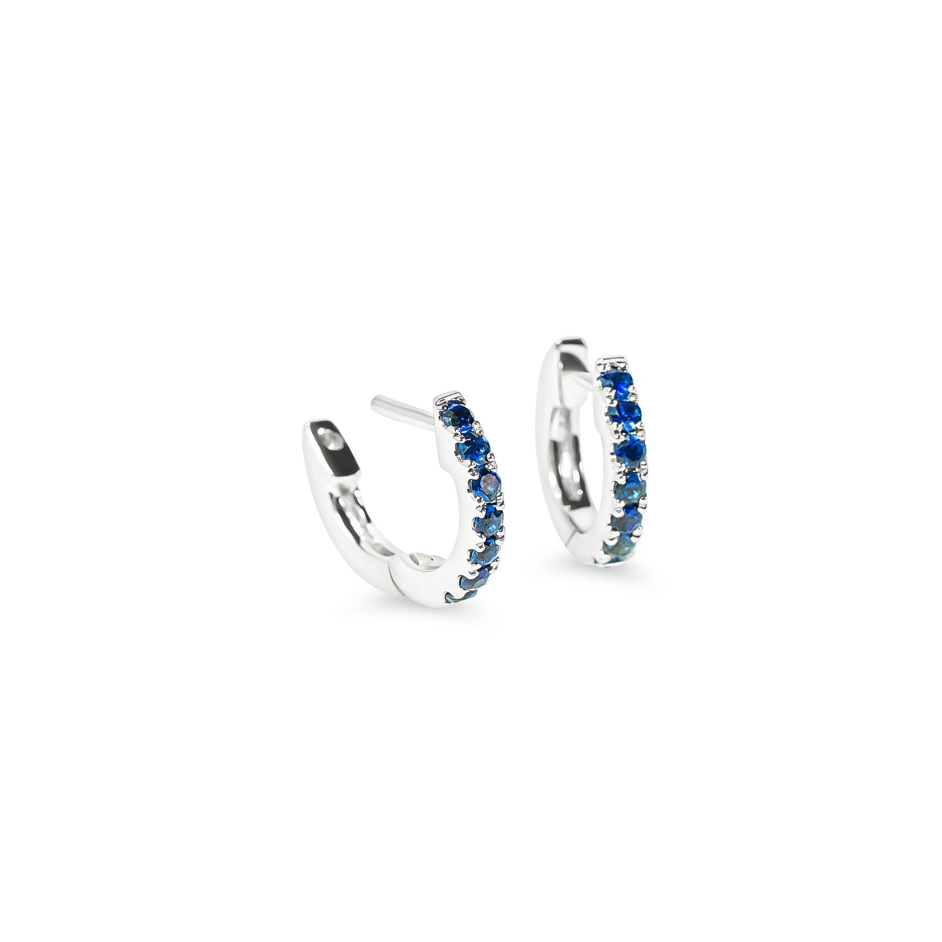 white gold huggie hoop earrings with blue sapphire on a white background