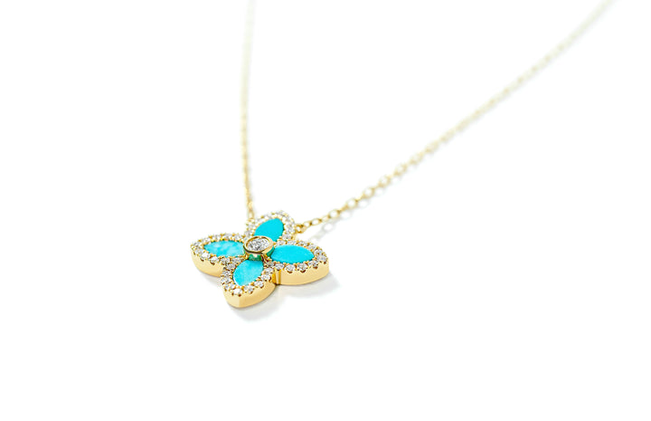 Gold necklace with a turquoise clover pendant with diamonds on a white background