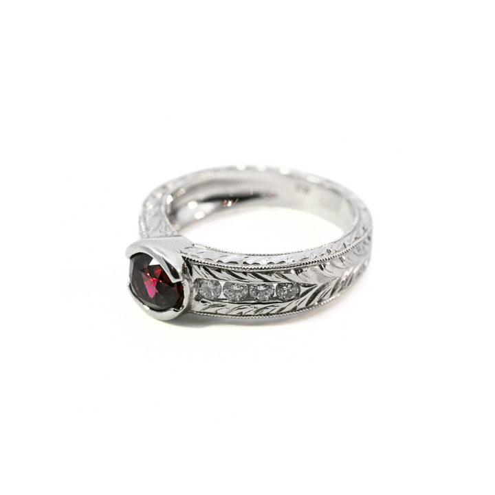 Platinum ring with a red spinel and small diamonds on a white background