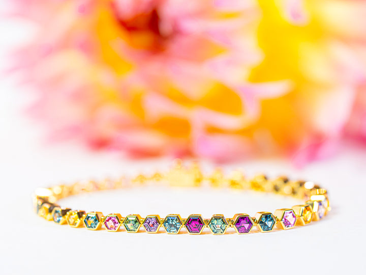 Gold bracelet with colorful sapphires on a multicolored background