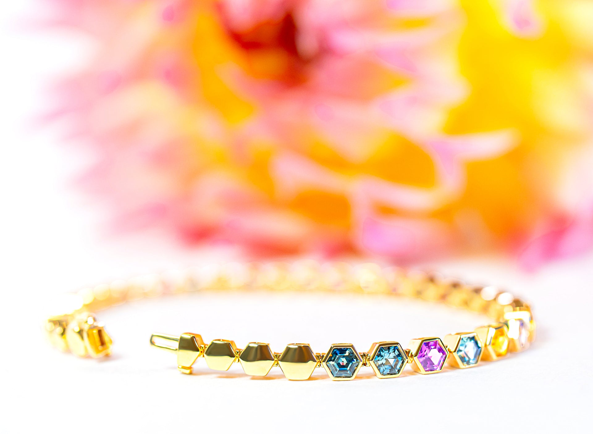 Gold bracelet with colorful sapphires on a multicolored background
