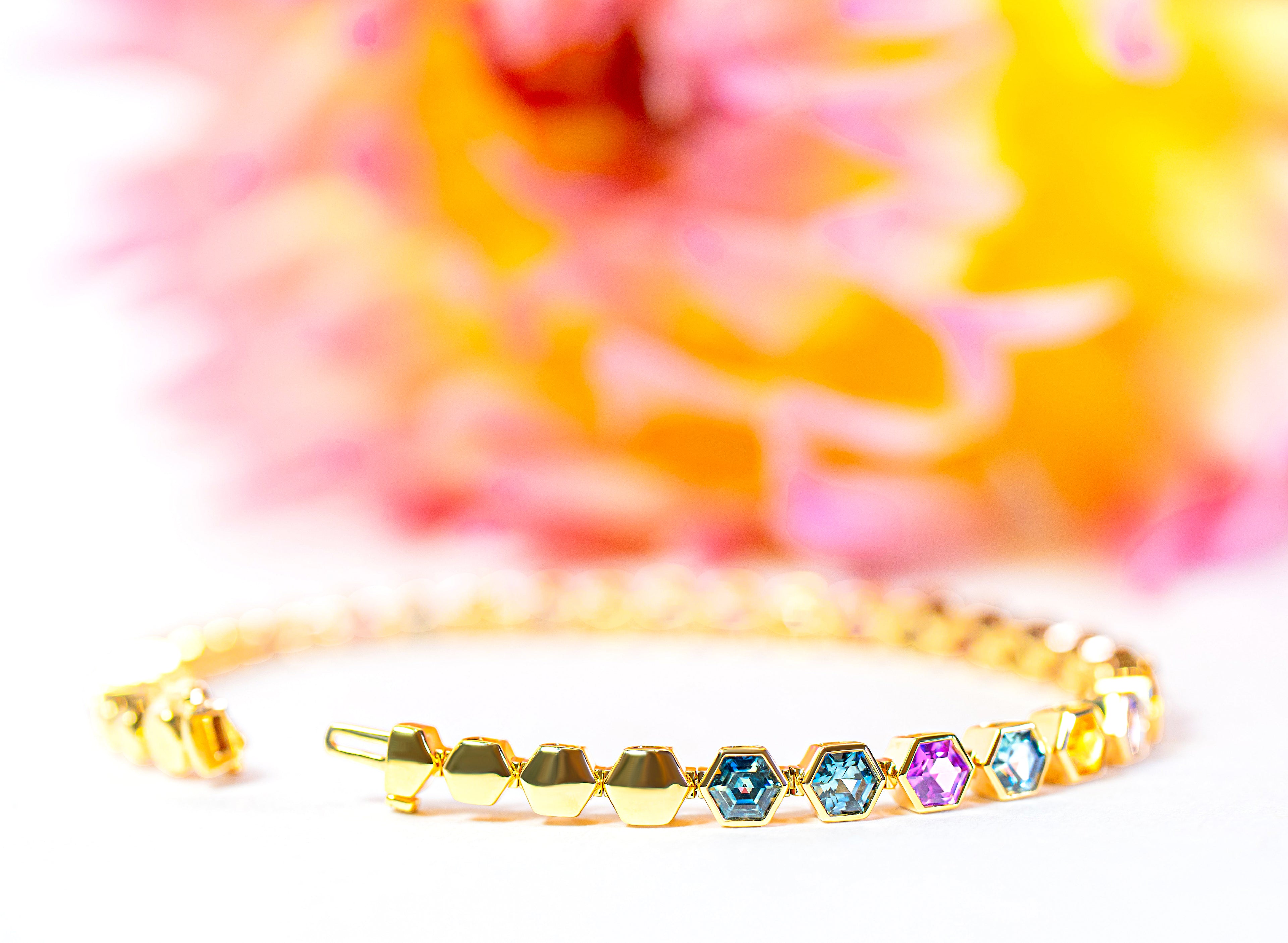 Gold bracelet with colorful sapphires on a multicolored background