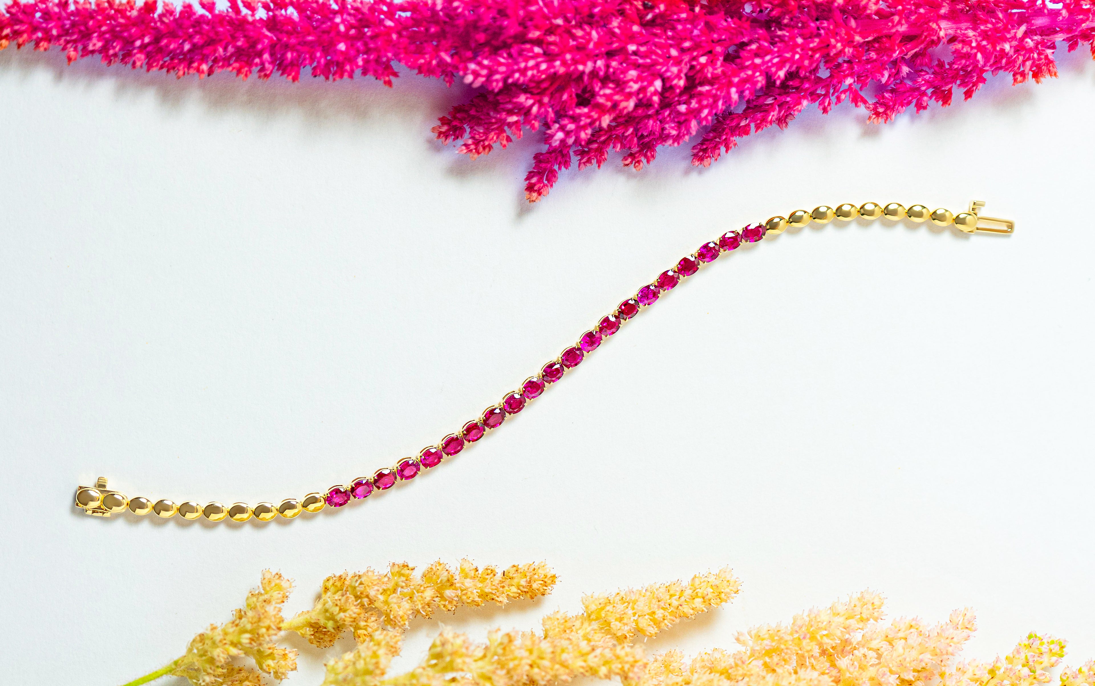 Gold bracelet with pink rubies on a white background
