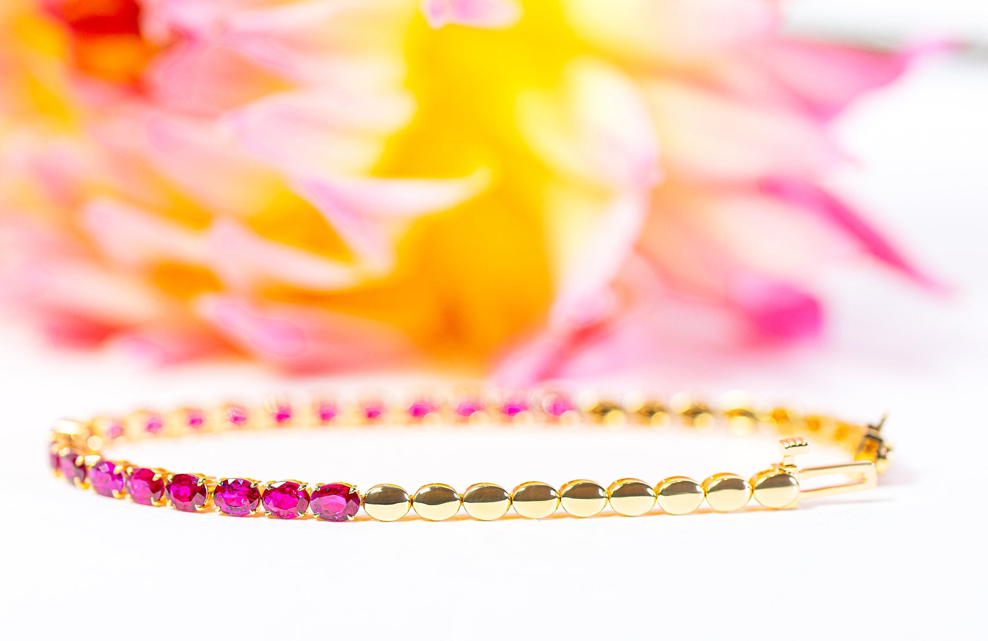 Gold bracelet with pink rubies on a colorful background