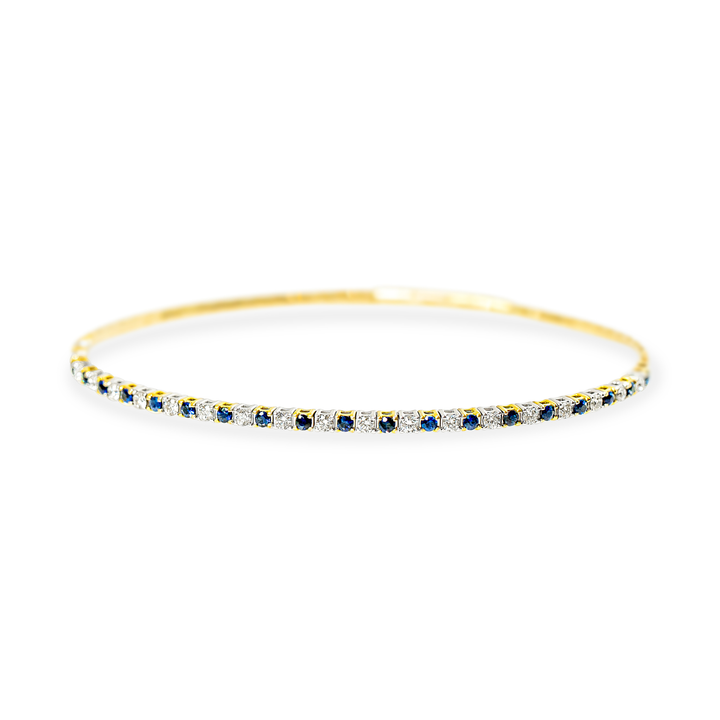 A dainty gold bangle bracelet featuring a continuous row of round-cut blue sapphires and white diamonds, set against a plain white background.