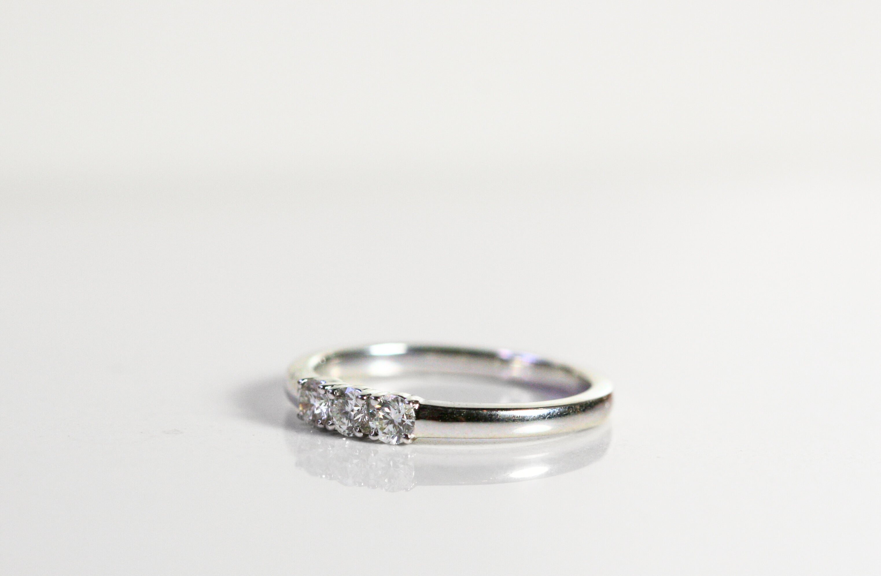 White gold ring with 3 round diamonds in the center. The band is thicker. This photo is a 3/4 view of the ring.