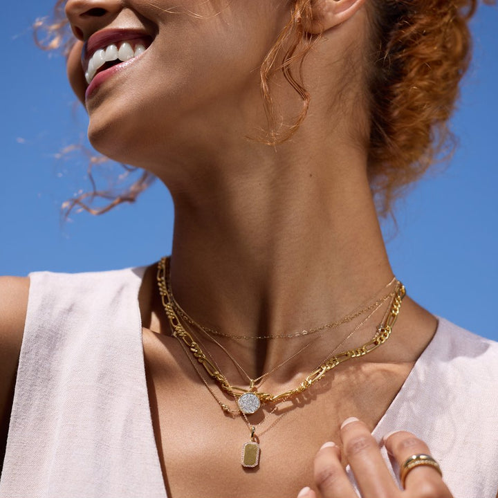 Woman wearing gold necklaces with a clear blue sky background