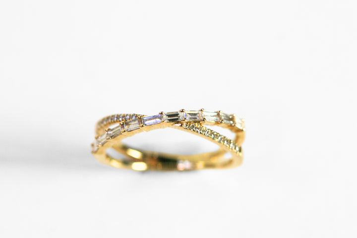 Ring shaped like an X. One arm of the X has round, brilliant cut diamonds. The other has horizontal baguettes. Set in yellow gold.