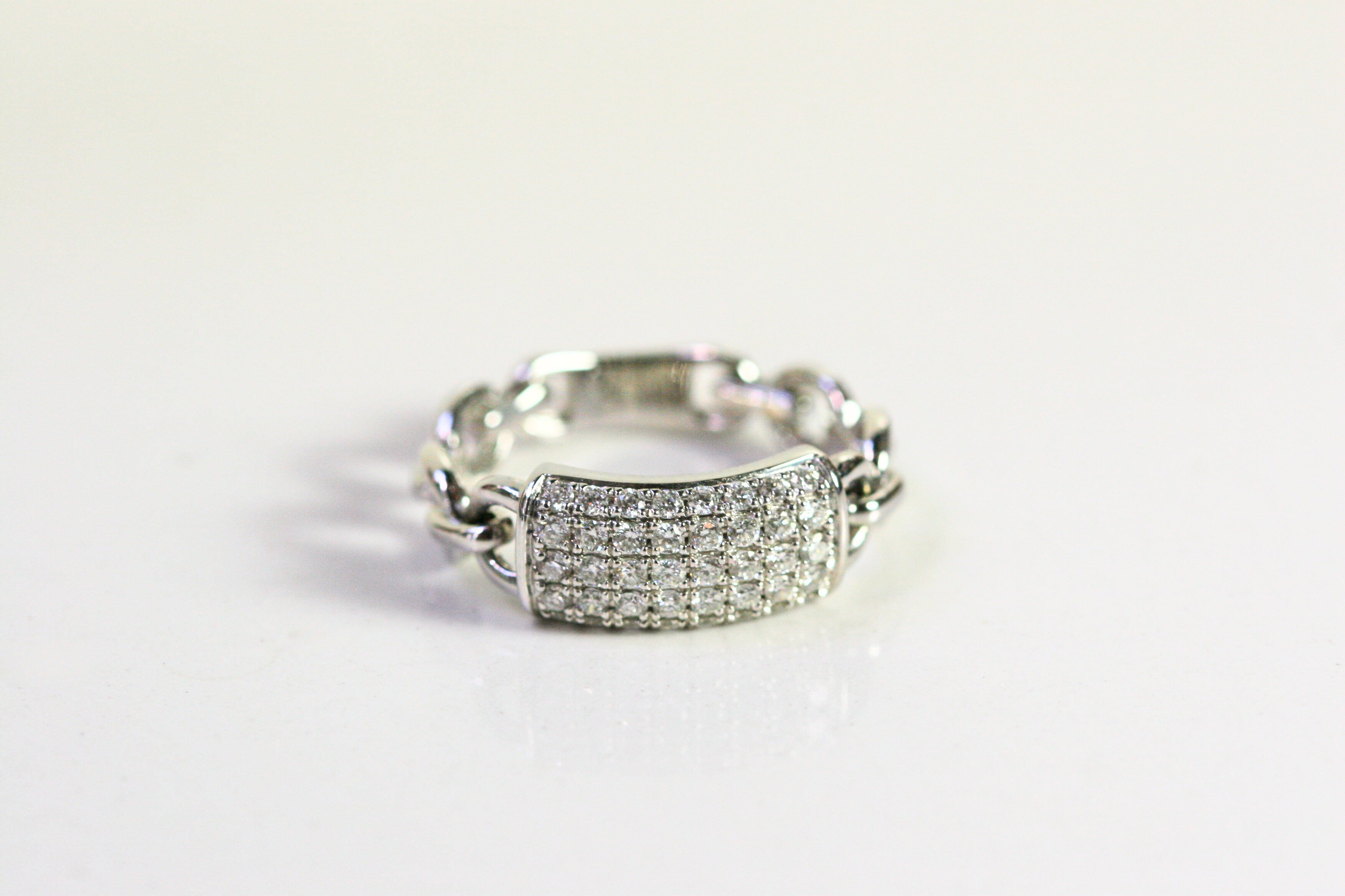 White gold ring. Front of the ring is a rectangle pave set with diamonds. The shank of the ring is a chain of white gold. 