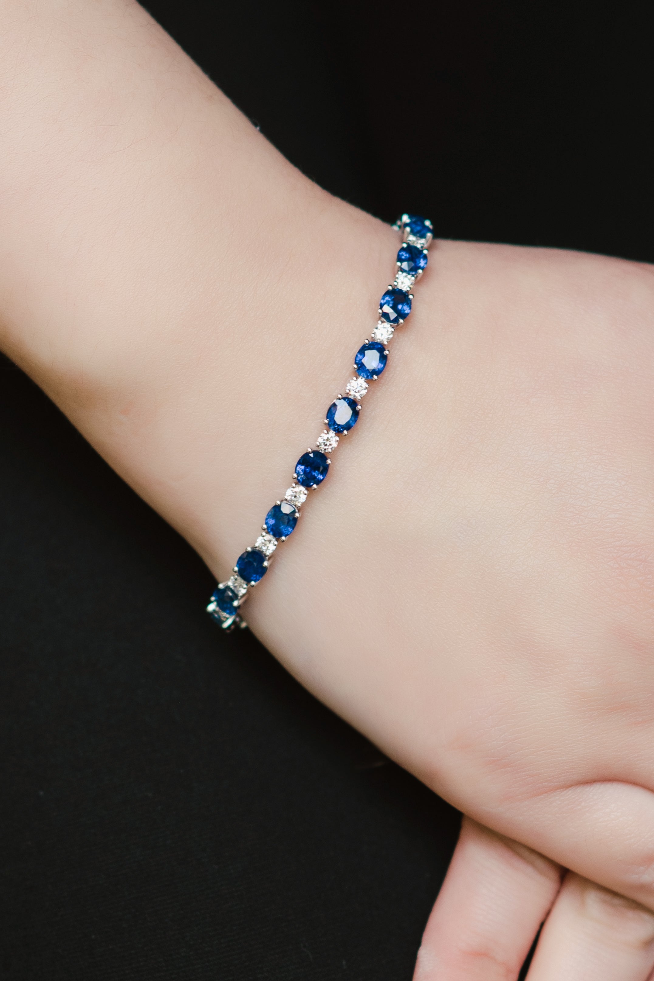 A bracelet featuring oval-cut blue sapphires and round-cut diamonds on a wrist.