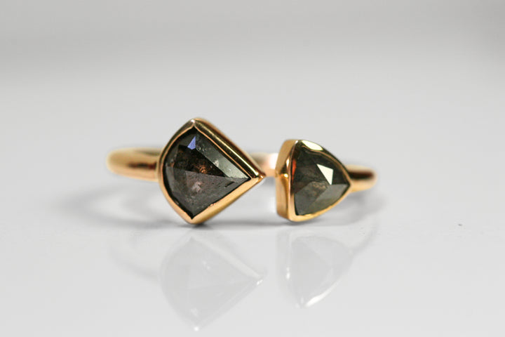 The two diamonds are both triangles, with a slight curve to them. Both diamonds are bezel set in yellow gold. They meet in the middle with a slight space between the two.