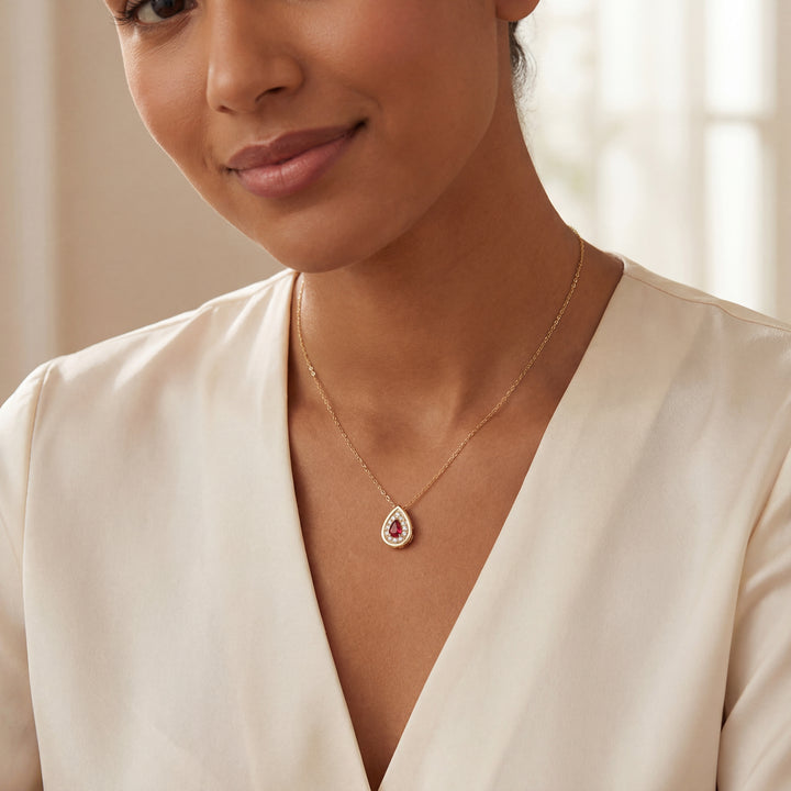 Woman wearing a delicate necklace with a teardrop ruby diamond pendant against a neutral background