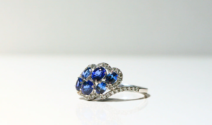 6 oval shaped sapphires float in an abstract, cloud-like shape - surrounded by diamonds. The front of the band is set with diamonds. The back half of the band is solid white gold.