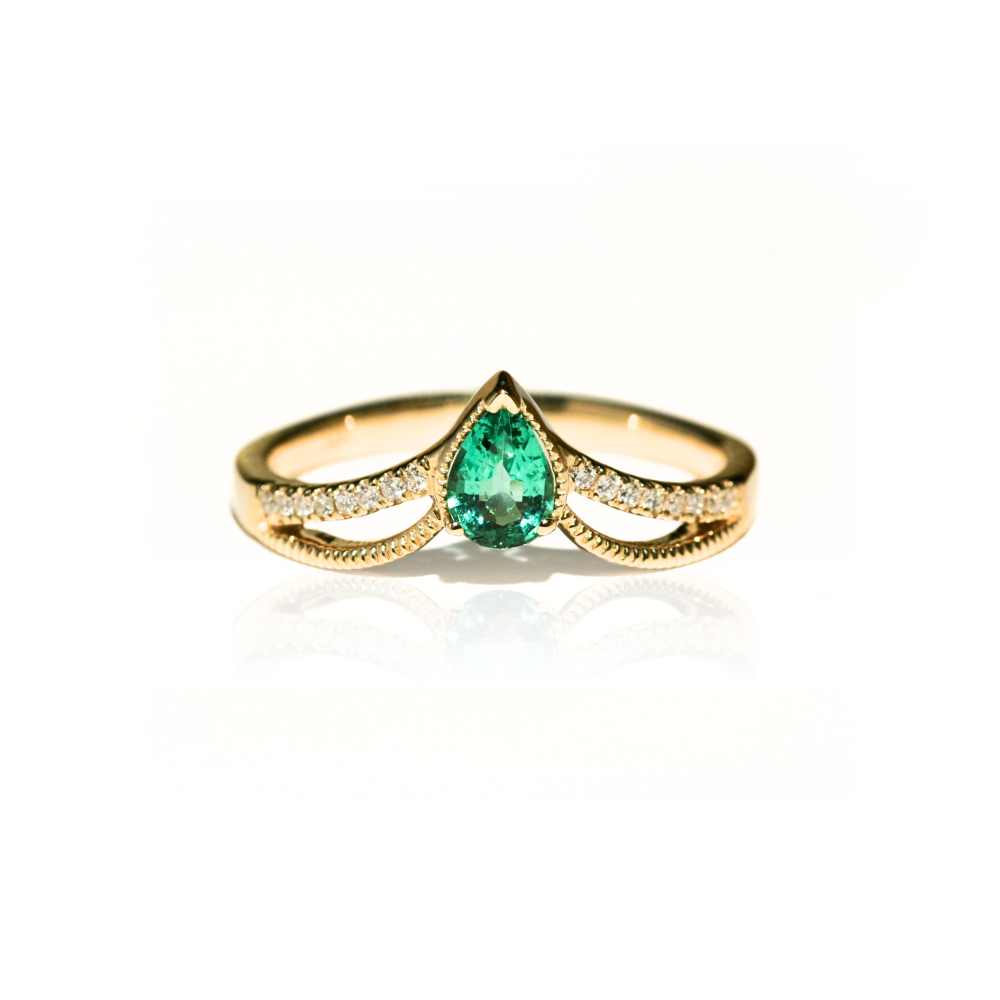 Gold ring with a pear-shaped emerald on a white background