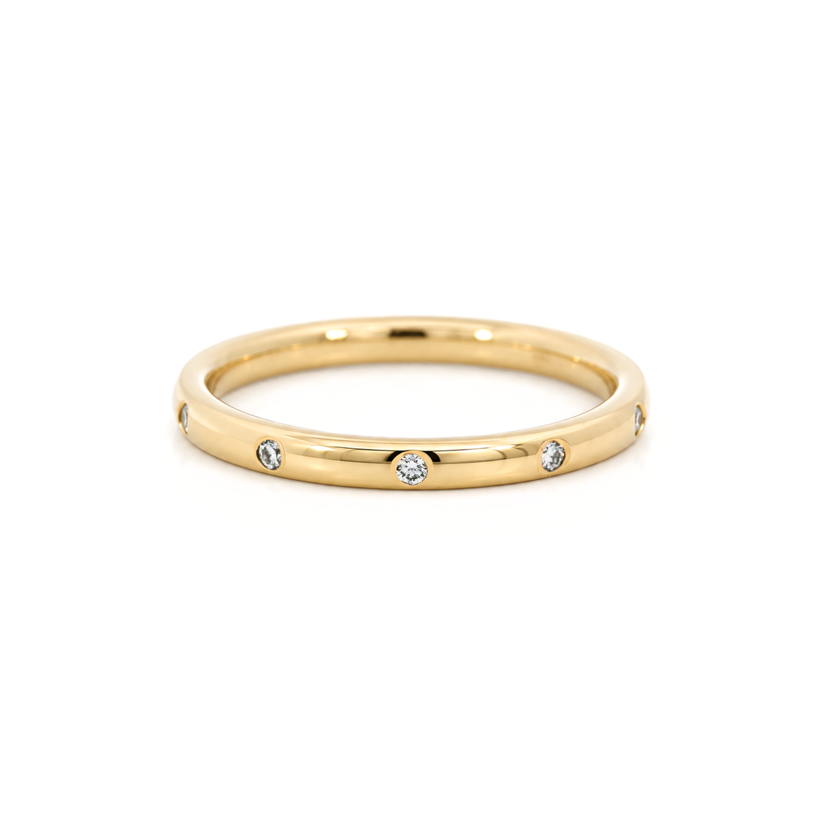A polished yellow gold band ring with small diamonds set along the band, photographed on a clean white background.