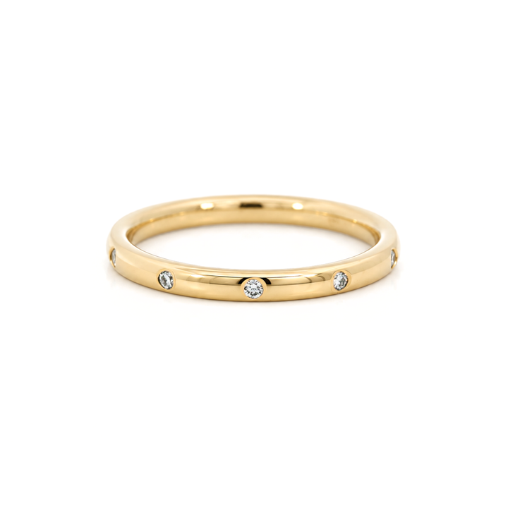 A polished yellow gold band ring with small diamonds set along the band, photographed on a clean white background.