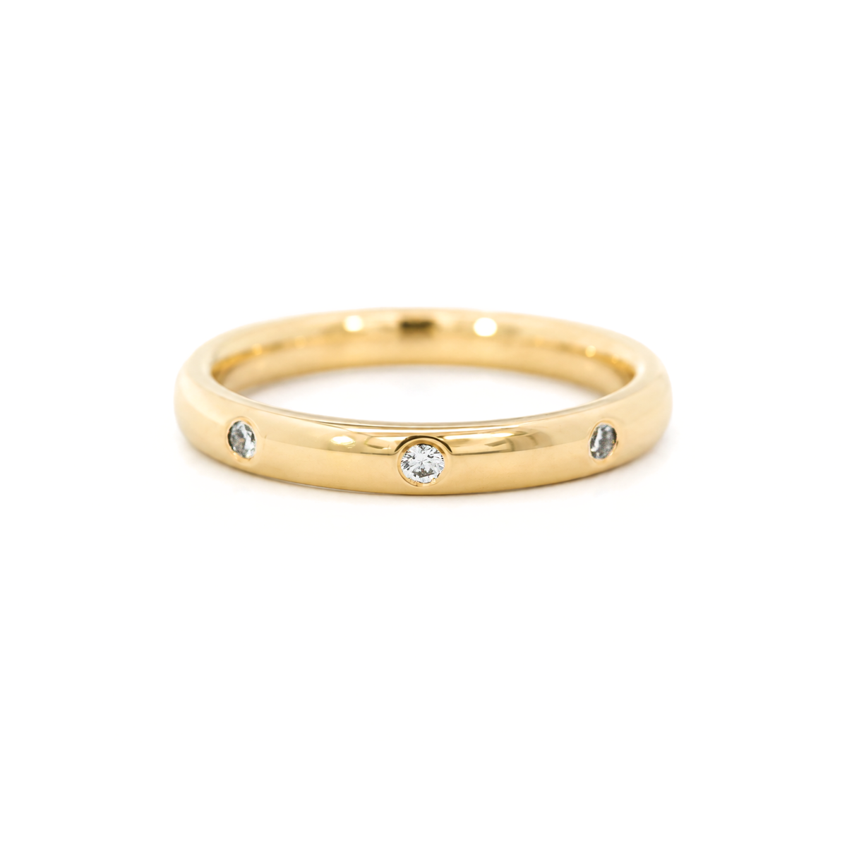 A yellow gold band ring featuring small round diamonds set into the band, photographed on a white background.